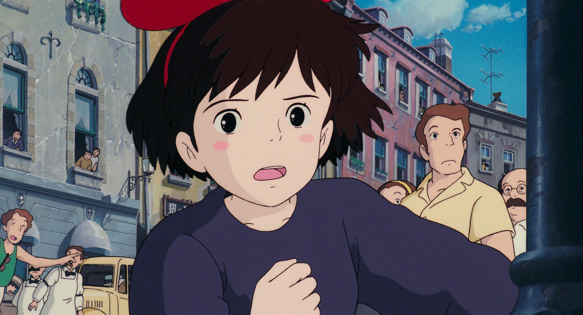Kiki flying above town in an official Studio Ghibli still